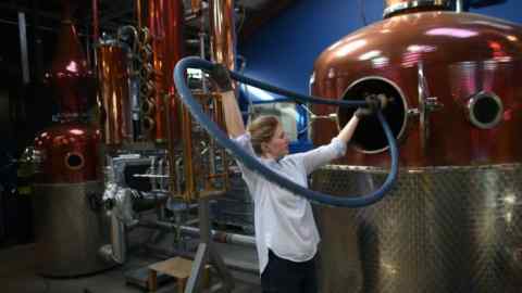 A man attaches a pipe to a pot sill in a brewery